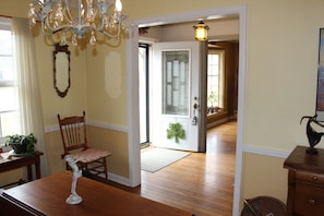 Cozy dining area with a wooden table and chair, featuring a chandelier and a door leading to another room.