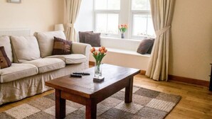 A living room with a sofa, a coffee table, and a window with curtains. - Old School by Interhome (Mid Skye)