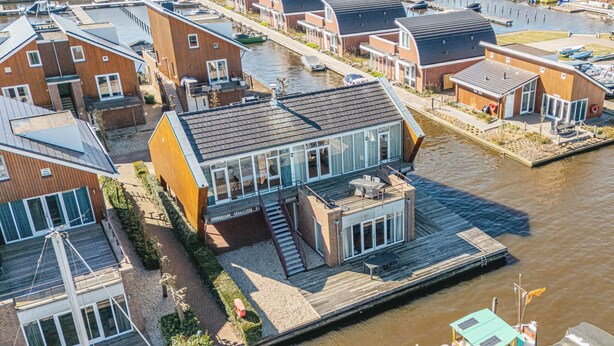 A modern houseboat with a deck and a small outdoor area, docked at a marina with other boats and houses. - Penthouse by Interhome (Uitgeest)
