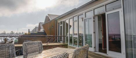 A rooftop terrace with wicker furniture and a glass door leading to a balcony.