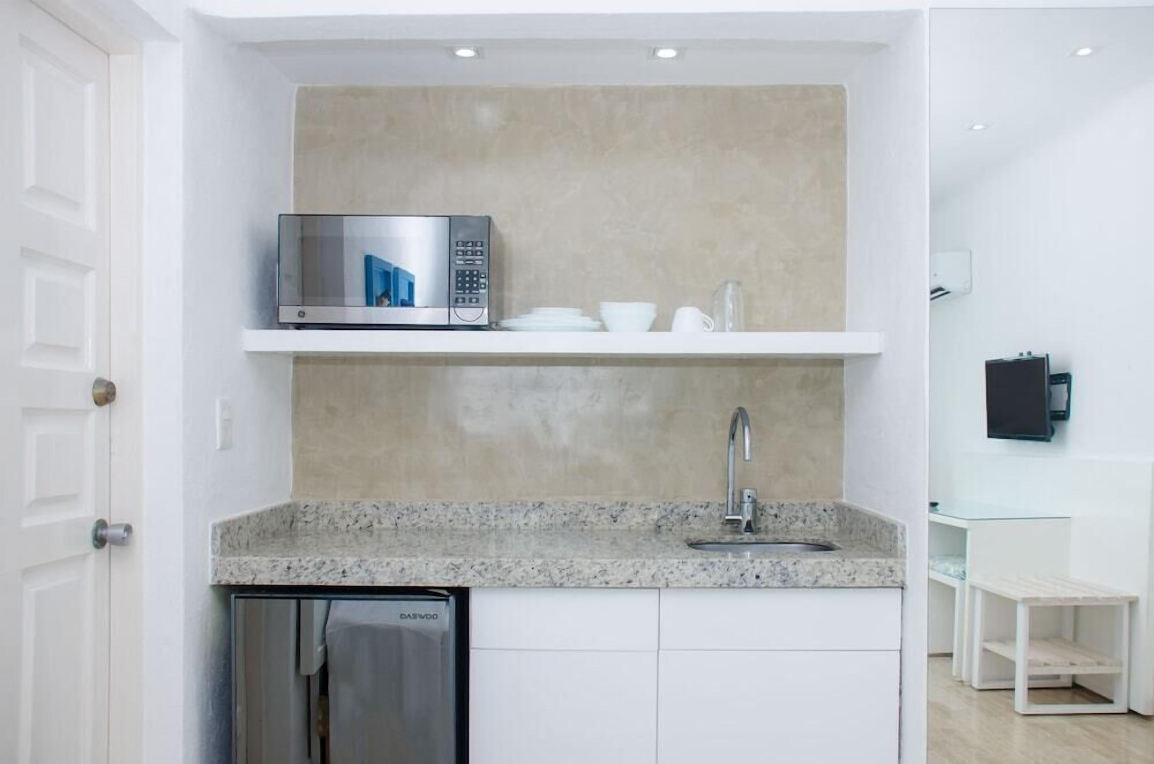 A compact kitchen with a built-in microwave, a sink, and a dishwasher.