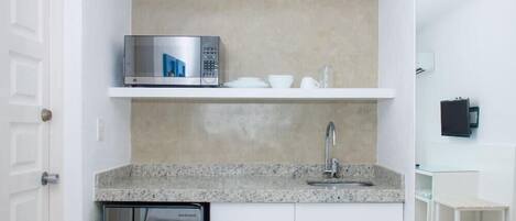 A compact kitchen with a built-in microwave, a sink, and a dishwasher.