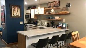 A modern kitchen with a central island, bar stools, and a dining table.
