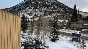 A mountain with snow-covered trees and a building with a yellow facade.