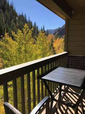 Enjoy the serene forest view from this balcony, featuring a metal table and chair.