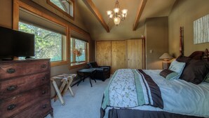 A bedroom with a bed, dresser, desk, chair, and a television.