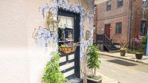 Un bâtiment avec une porte bleue, un petit porche avec des marches et des plantes en pot.