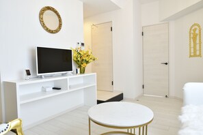 Una sala moderna con una televisión de pantalla plana, una consola blanca y una mesa redonda.