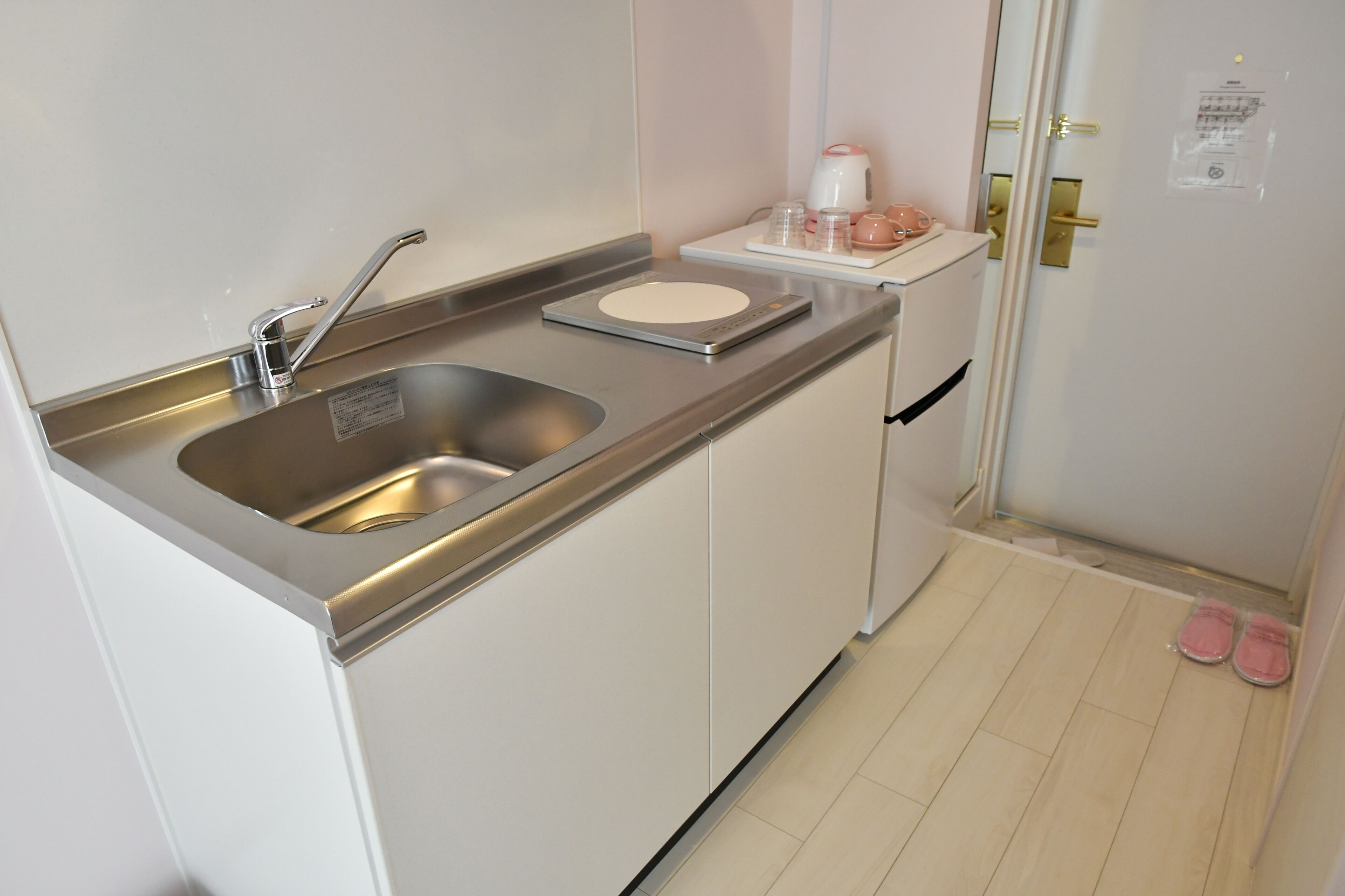 A compact kitchen with a double sink, a small countertop, and a refrigerator.