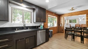 Une cuisine moderne avec des meubles en bois foncé, des appareils électroménagers en acier inoxydable et un coin repas comprenant des chaises et une table en bois.