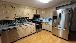 A modern kitchen with wooden cabinets, stainless steel appliances, and a tiled backsplash. - The Family Escape Ranch (Erie)