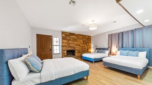 Una camera da letto con tre letti, un muro in pietra e un pavimento in legno.