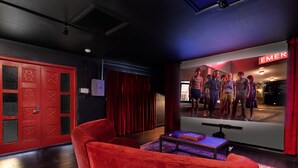 Un divano in velluto rosso, uno schermo televisivo e una porta rossa con pannelli decorativi.