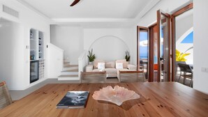 Una sala de estar moderna con piso de madera, un juego de sofá, una mesa de centro de vidrio y un ventilador de techo.