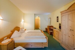 A hotel room with two wooden beds, a wooden wardrobe, a desk with a chair, and a mirror. - Hotel Eschbacher (Filzmoos)