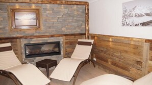 Una habitación acogedora con chimenea, dos sillones de descanso y una pared de piedra.