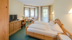 Habitación de hotel con cama de madera, escritorio con televisor y una silla.