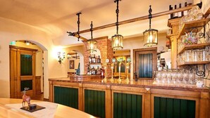 Un rincón de bar con armarios de madera, mostrador y lámparas colgantes.