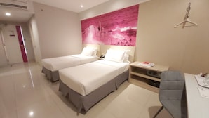 A hotel room with two beds, a desk with a chair, a large pink abstract painting on the wall, and a hanger on the wall. - d'primahotel Balikpapan (Balikpapan)