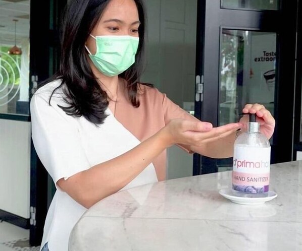 A person using a hand sanitizer dispenser on a marble table.
