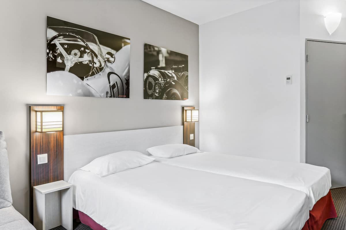 Een hotelkamer met een groot bed, twee wandlampen en twee ingelijste foto's aan de muur.