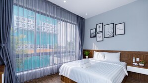 A modern hotel room with a large window, a neatly made bed, and a wall with framed pictures. - Tran Duy Sunrise Villa (Ho Chi Minh City)