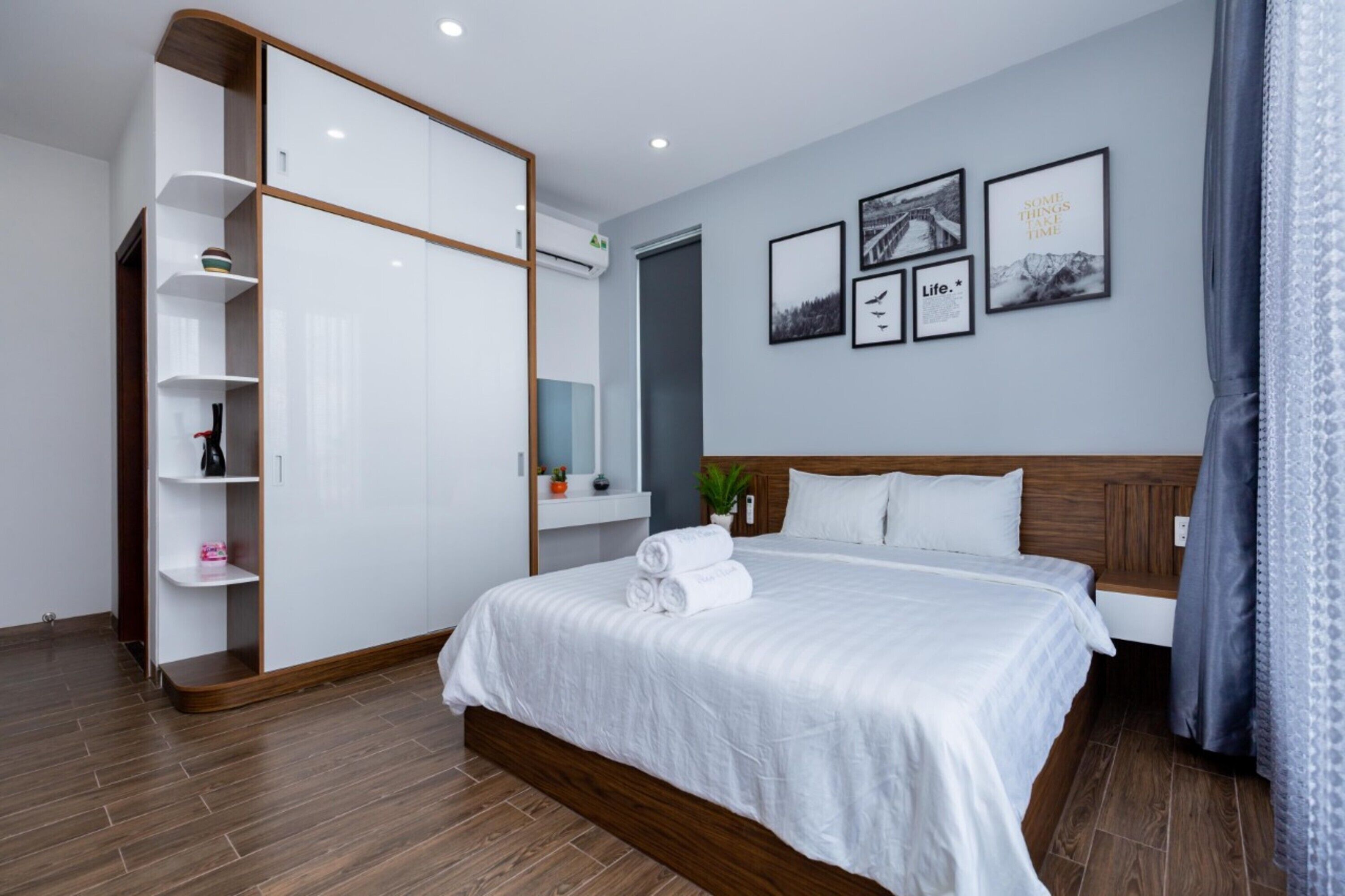 A modern hotel room with a large bed, a wardrobe, and a small seating area.