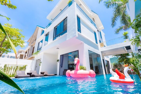 A modern hotel with a swimming pool, featuring a pink flamingo float and a swan float.