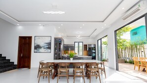 A modern kitchen with a central island, built-in cabinets, and a large window. - Tran Duy Sunrise Villa (Ho Chi Minh City)