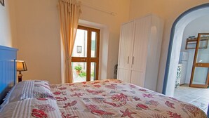 Un dormitorio con cama, armario y puerta que da a un balcón.