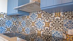 Una cocina con armarios azules, un lavamanos de acero inoxidable y un salpicadero de azulejos estampados.