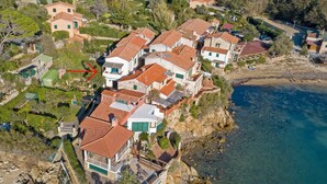 Zona residencial costera con casas de techo rojo, algunas con balcones, y una playa cerca.