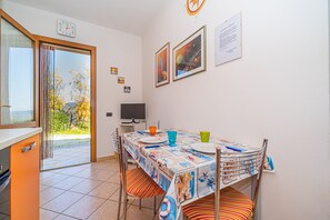 Un comedor con una mesa dispuesta para dos, un televisor y una ventana con cortinas.