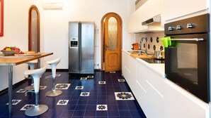 Eine Küche mit Kühlschrank, Backofen und Barhocker.