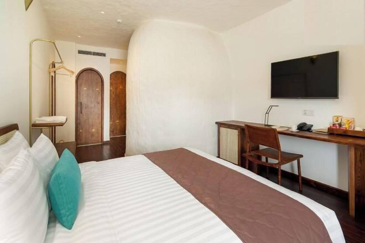 Une chambre d’hôtel comprenant un lit, un bureau, une chaise, une télévision et une armoire.