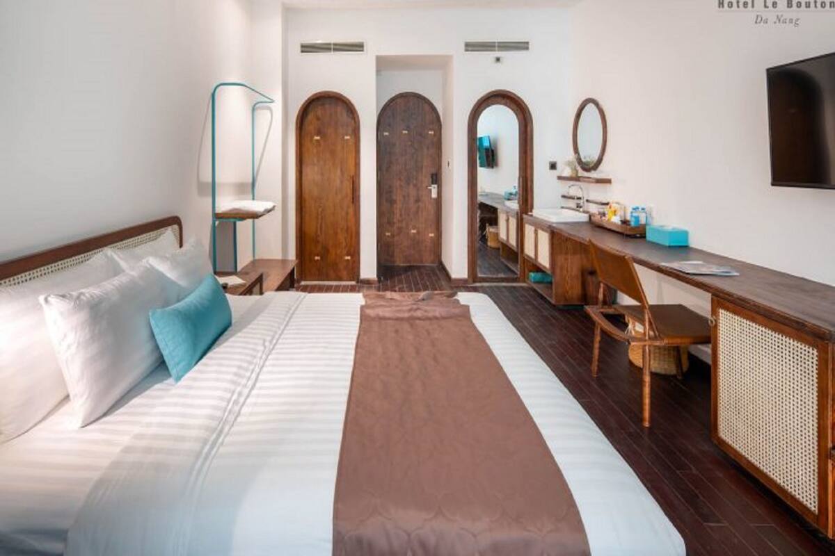 Une chambre d’hôtel équipée d’un lit, d’un bureau, d’une chaise, d’un miroir et d’une télévision.