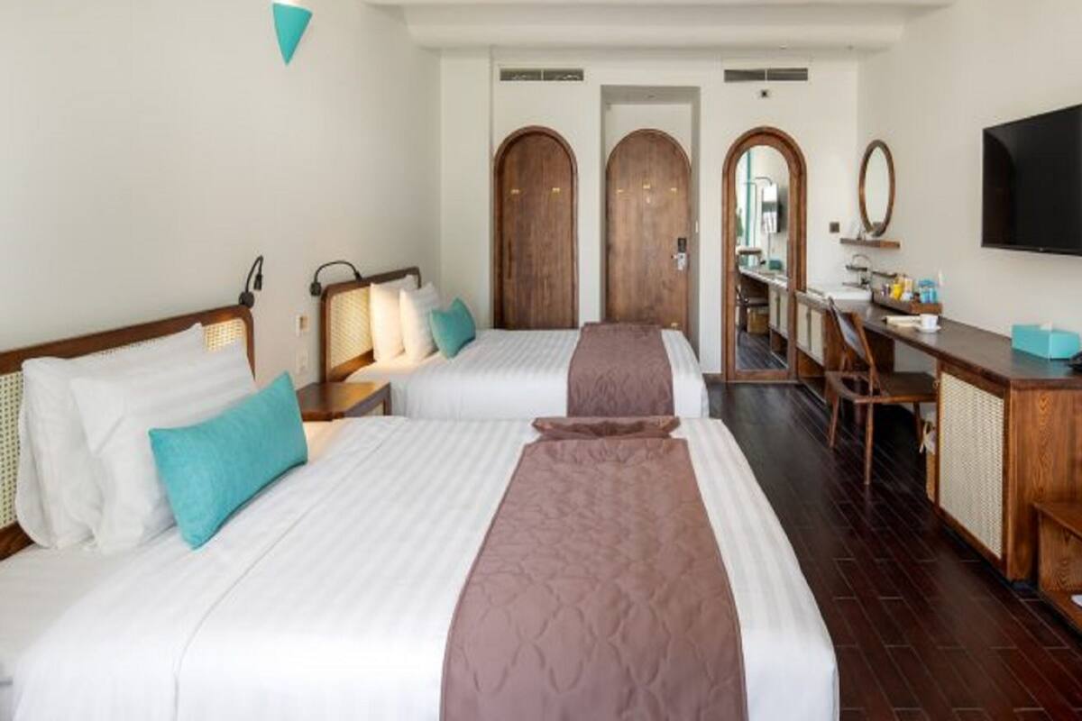 Une chambre d ’hôtel avec deux lits, un bureau, une télévision et un miroir.