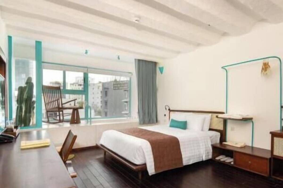 Une chambre d’hôtel comprenant un lit, un bureau, une chaise, une fenêtre avec vue et une table de chevet.