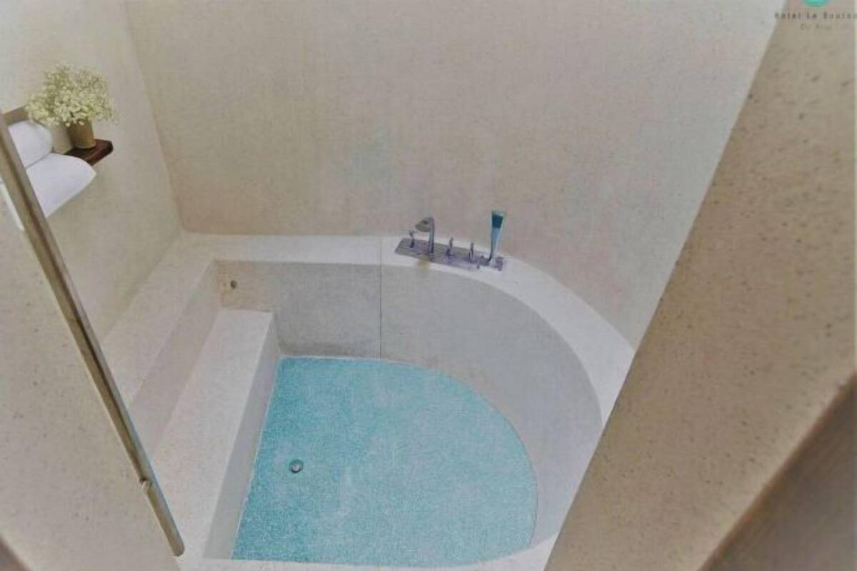 Une baignoire avec un petit bassin, un porte-serviettes et une plante en pot.