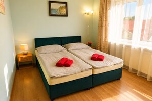 Un lit double avec deux serviettes rouges, une lampe de chevet et un tableau accroché au mur.