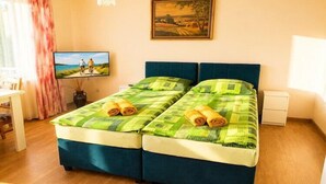 A double bed with green bedding, a television on the wall, a painting above the bed, and a small bedside table. - Holiday Home near Baltic Sea & Sandy Beaches (Miedzyzdroje)
