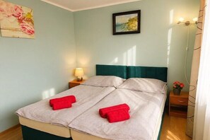Una cama doble con cabecera color turquesa, una mesita de noche con lámpara y un cuadro en la pared.
