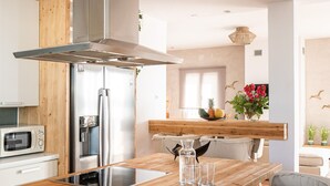 Een moderne keuken met een houten kookeiland, roestvrijstalen apparatuur en een groot raam.