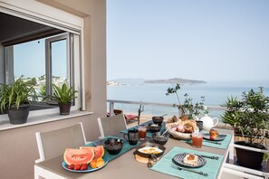 Une table dressée pour le petit-déjeuner, avec vue sur la mer et une île au loin.