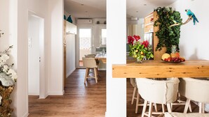 Een moderne keuken met een houten kookeiland, witte stoelen en een decoratieve plantenwand.
