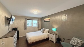 Une chambre à coucher avec un lit, une table de chevet, une lampe et une fenêtre.