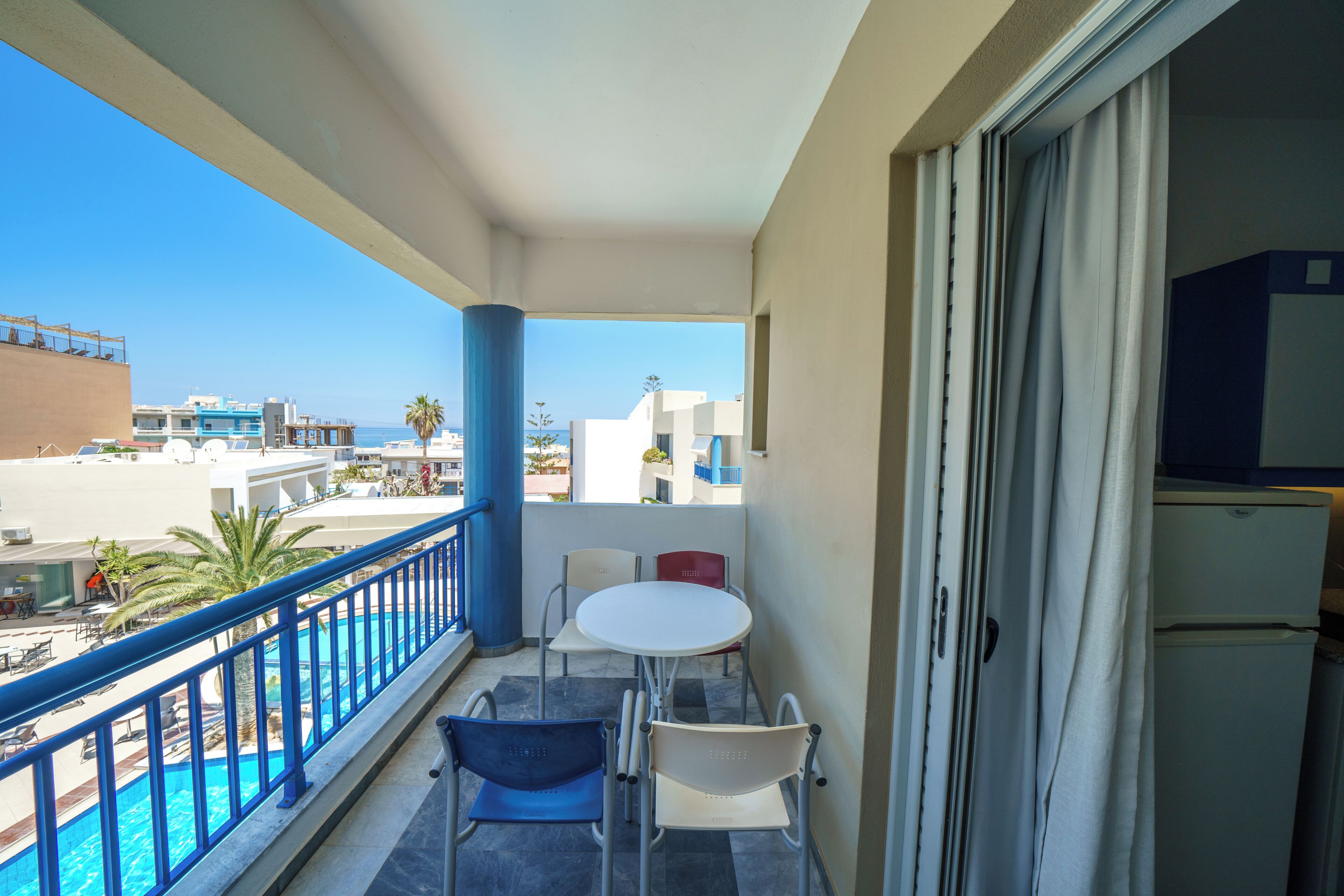 A balcony with a pool, chairs, and a table.