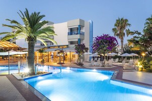 Una piscina al aire libre, sombrillas, sillones reclinables de piscina