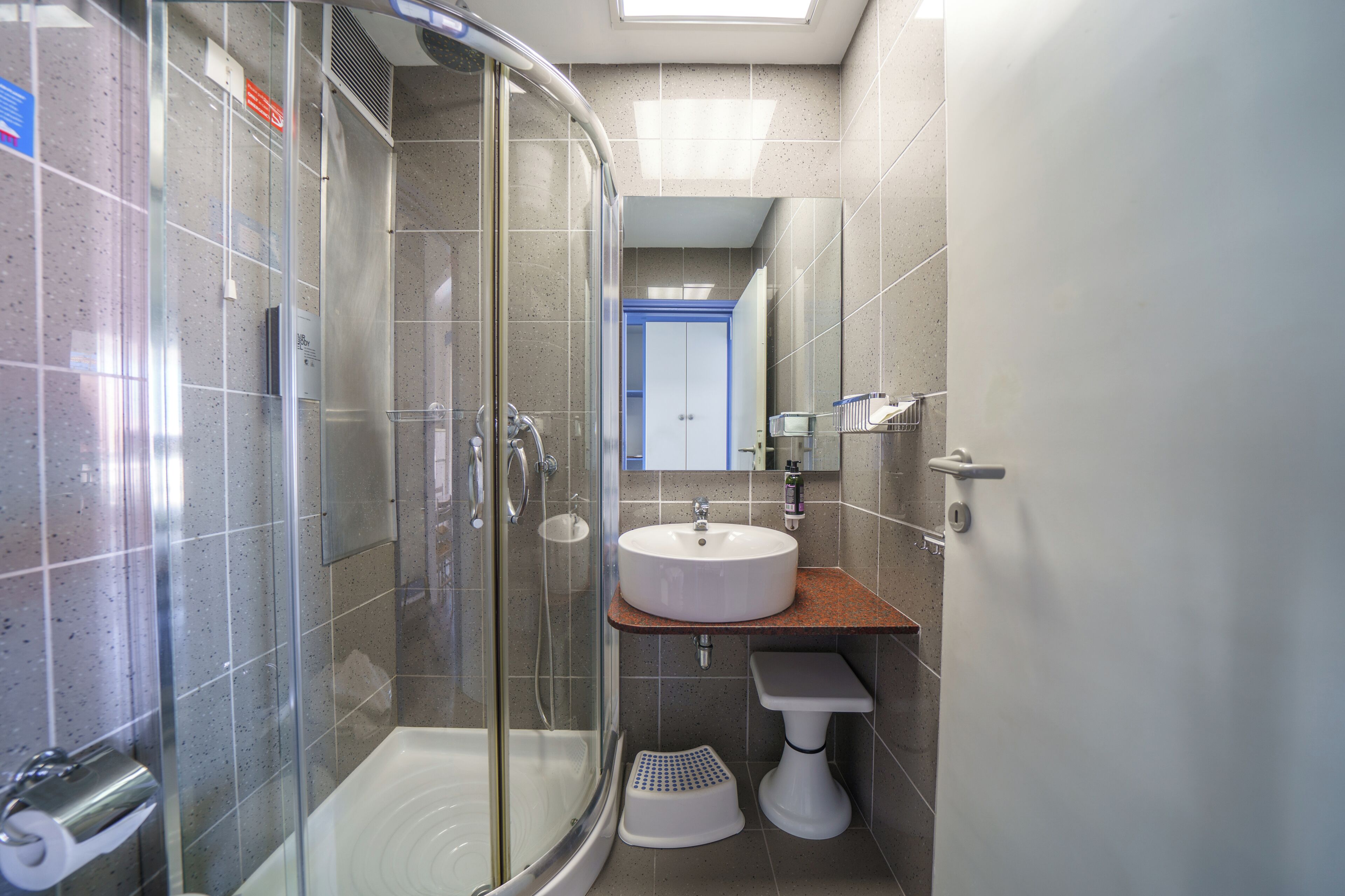 A bathroom with a glass-enclosed shower, a sink, and a toilet.