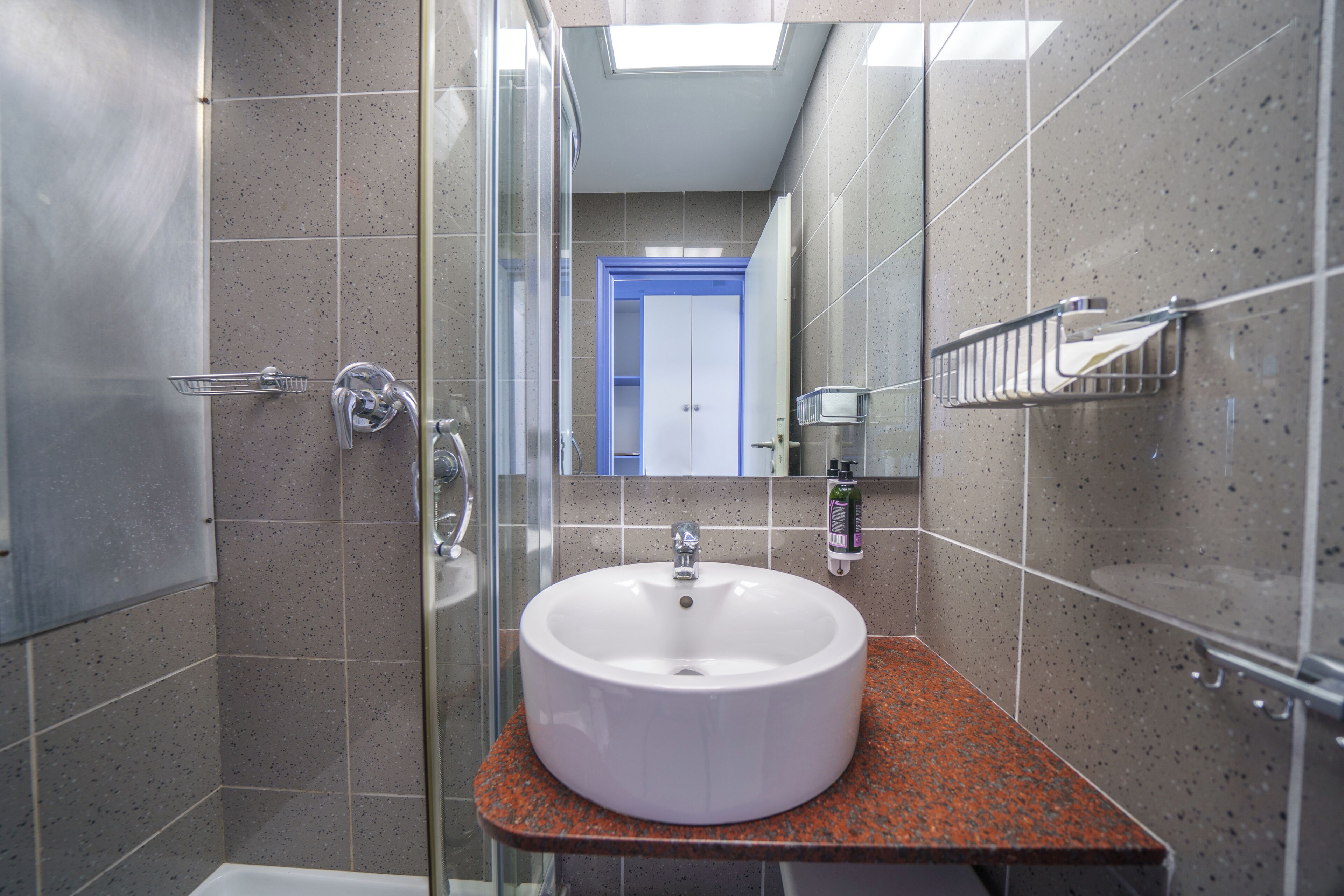A bathroom with a white sink, a glass shower enclosure, and a blue door in the background.